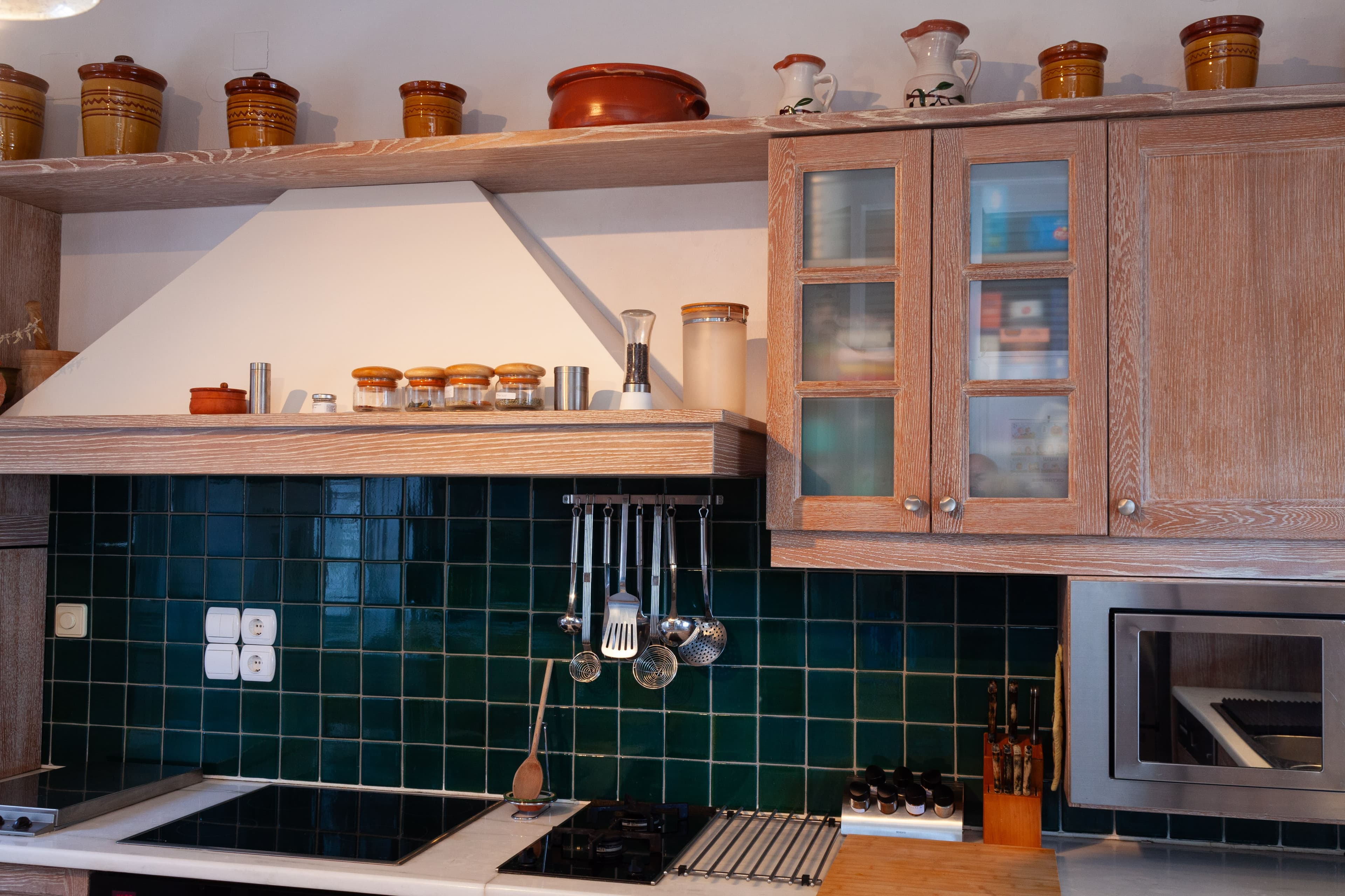 The green tiled splashback, utensils hung above the hob