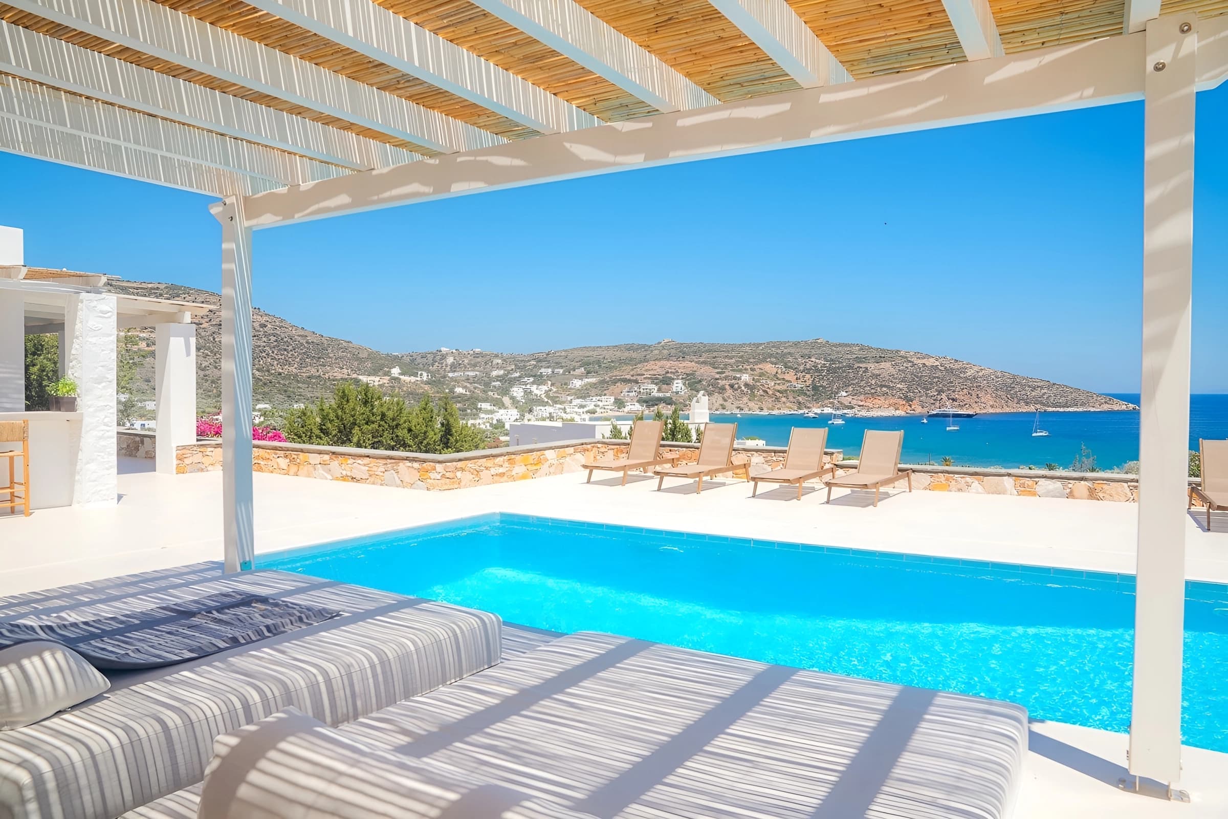 Daybeds under the pergola, the pool and Platis Gialos bay beyond