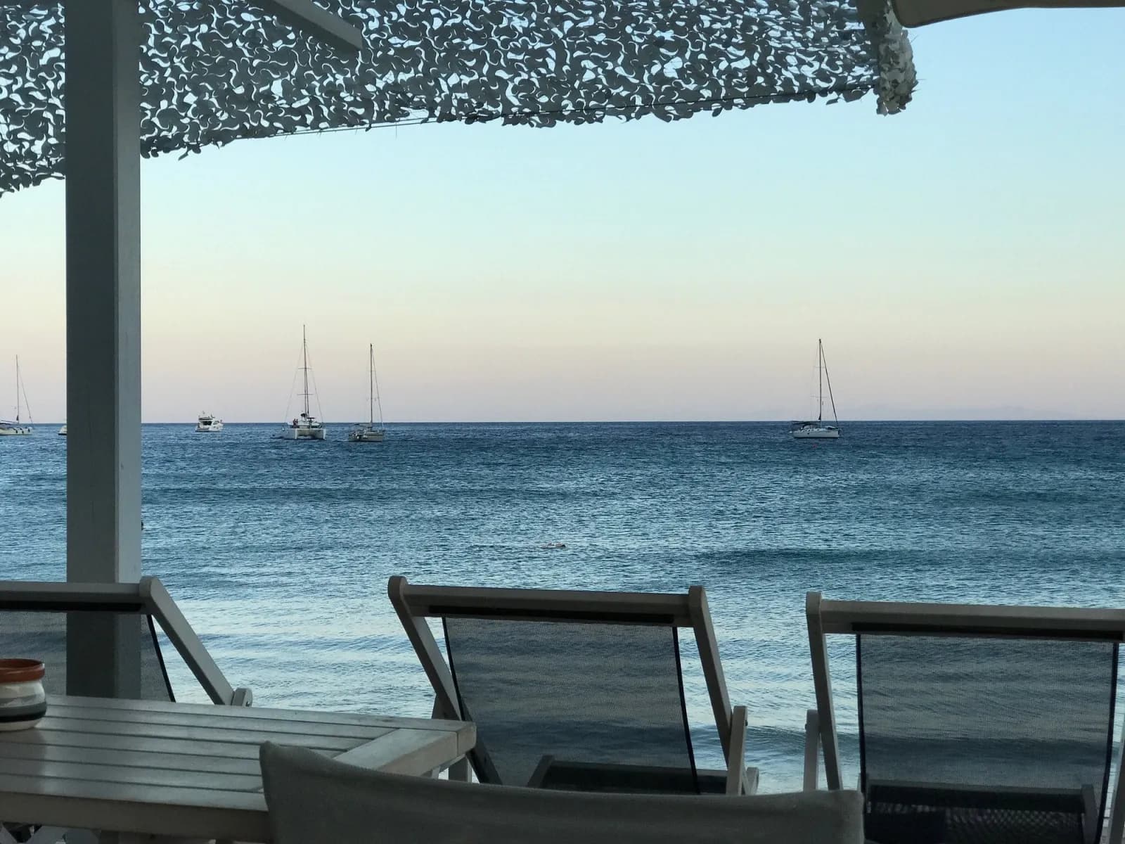 Platis Gialos at dusk, sailboats anchored in the bay and the tavernas on the sand, a 7-minute walk below the villa